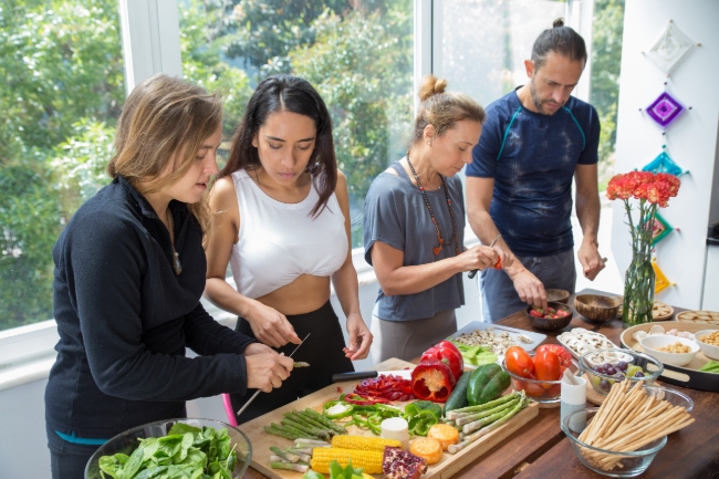 Men and women cutting vegetables